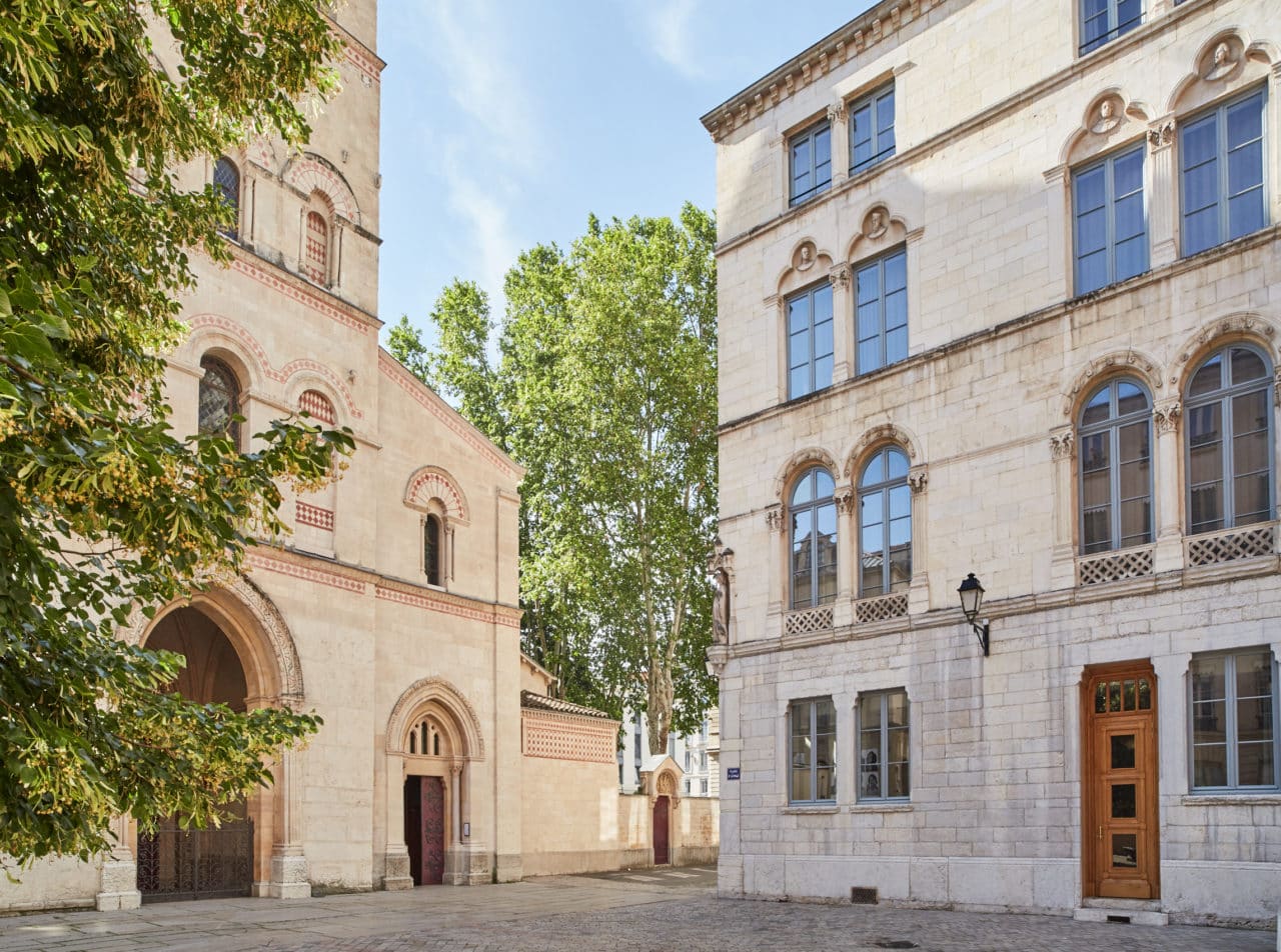 Place de l'Abbaye avec à gauche, la façade de la Basilique - Abbaye Saint-Martin d'Ainay et, à droite, la façade de l'Hôtel de l'Abbaye et du Café Basilic